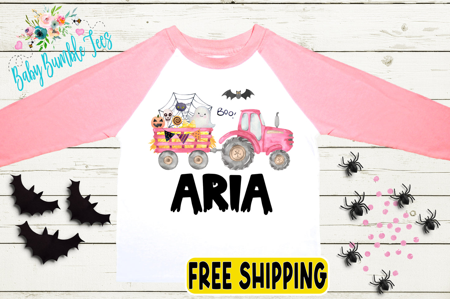 a pink and white long-sleeved shirt with a Halloween-themed design, including a tractor, bats, and a spider. The shirt has the name "Aria" printed on it.