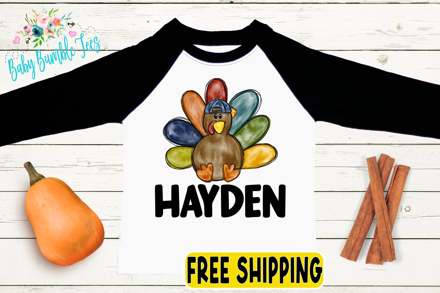 A white and black long-sleeved shirt with a colorful turkey graphic and the name "Hayden" printed on it, along with a pumpkin, cinnamon sticks, and a "FREE SHIPPING" label.