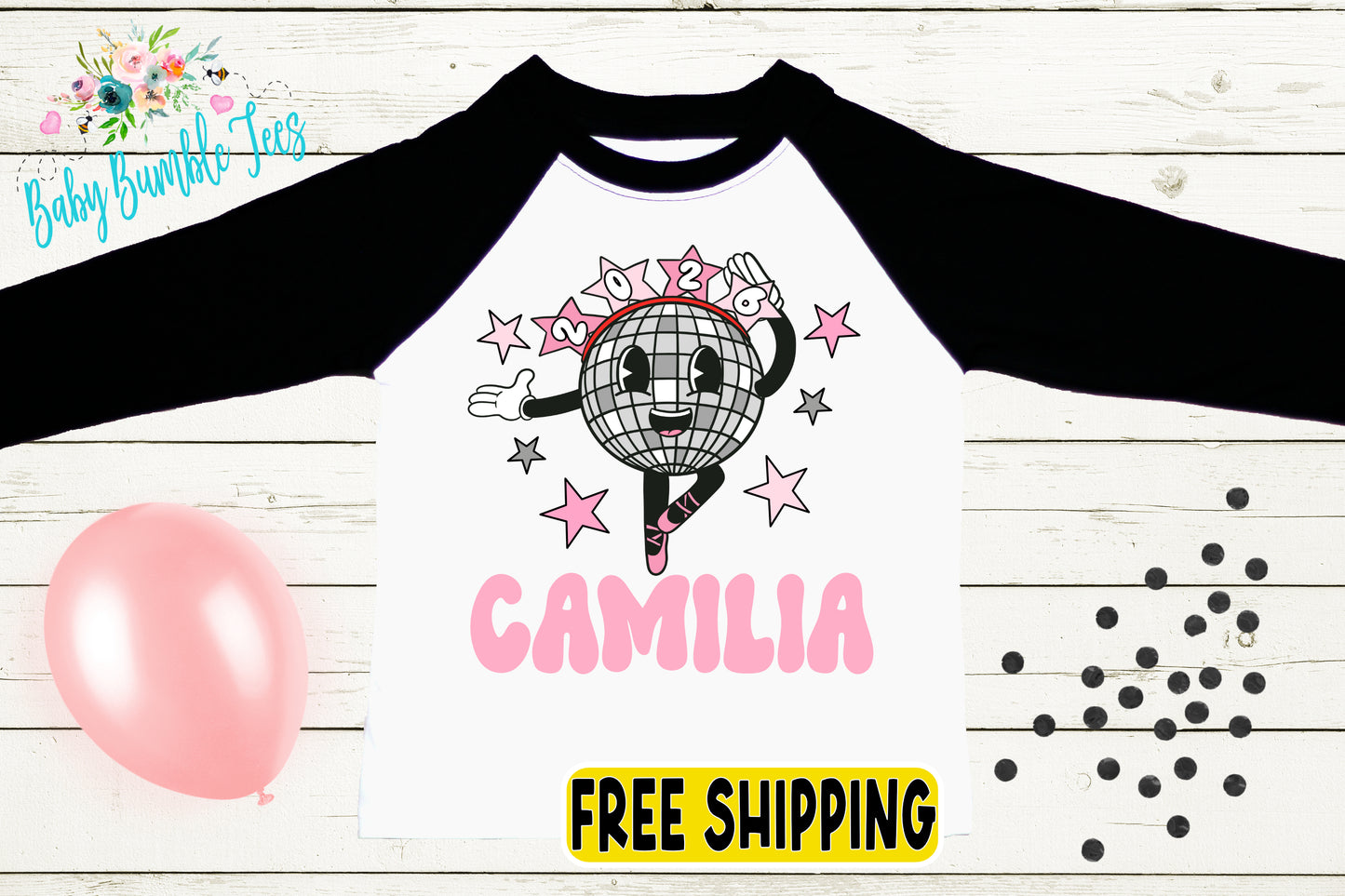 a white and black long-sleeved shirt with a cartoon image of a dancing disco ball and the name "CAMILIA" printed on it. The shirt is displayed on a wooden surface, with a pink balloon and scattered black dots in the background.