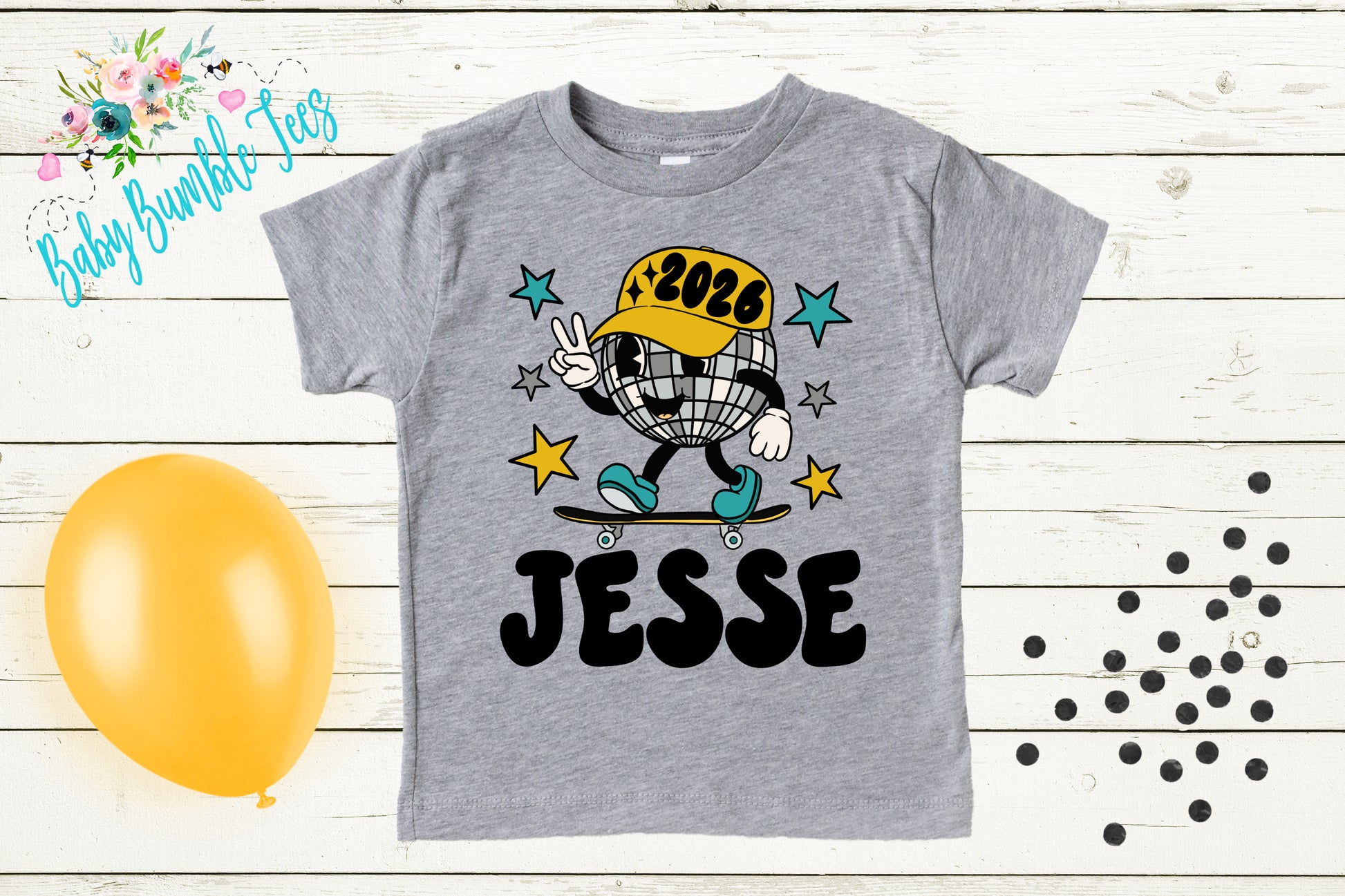 A gray t-shirt with a cartoon image of a disco ball and a skateboard, along with the text "JESSE" and a yellow balloon.